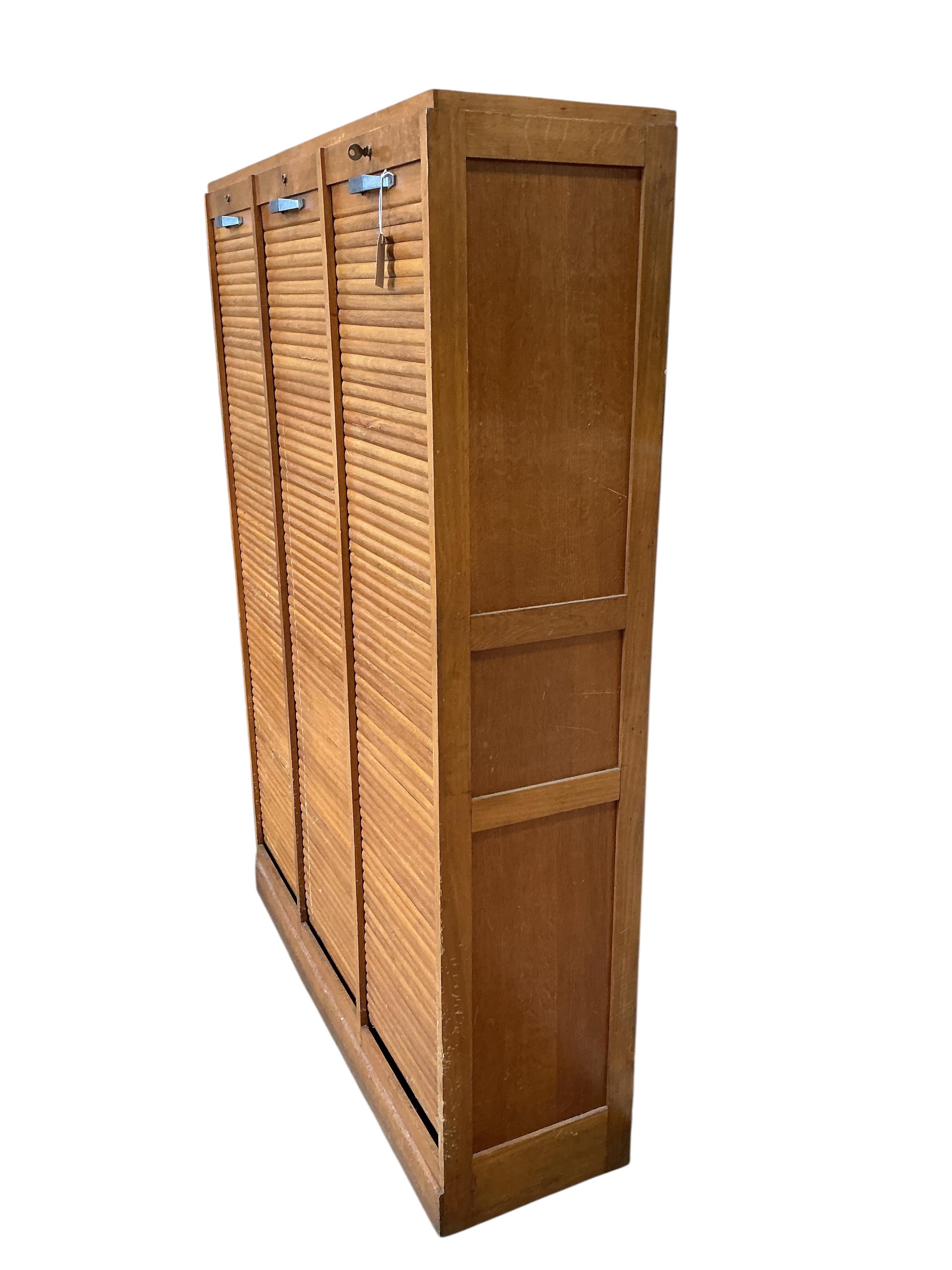 A mid 20th century oak triple tambour filing cabinet, width 126cm, depth 38cm, height 180cm
